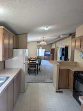 Kitchen featuring light floors, black range with gas stovetop, light countertops, and pendant lighting