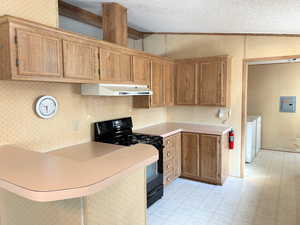 Kitchen with light floors, black gas stove, separate washer and dryer, under cabinet range hood, and wallpapered walls