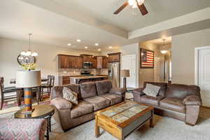 Living room with recessed lighting, ceiling fan with notable chandelier, and carpet