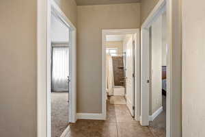 Corridor with tile patterned flooring, carpet, and baseboards