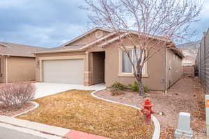 View of front facade with stucco siding, driveway, a garage, and fence