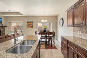 Kitchen featuring a sink, a notable chandelier, light stone countertops, and backsplash