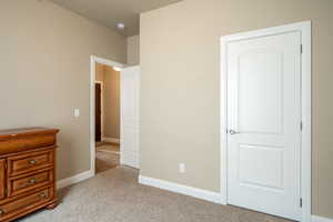 Unfurnished bedroom with baseboards and light colored carpet
