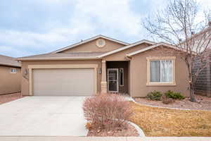 Ranch-style home with stucco siding, a garage, driveway, and a shingled roof