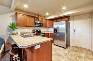 Kitchen with light countertops, appliances with stainless steel finishes, a sink, and a peninsula