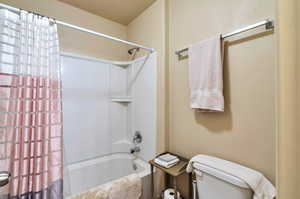 Full bathroom featuring toilet and shower / tub combo with curtain