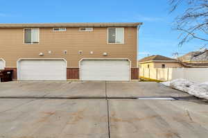 Back of house featuring driveway, an attached garage, fence, brick and siding