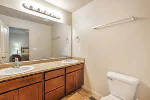 Full bath featuring double vanity, a sink, toilet, and connected bathroom