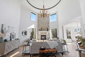 Living room with a wealth of natural light, a fireplace, a notable chandelier, and wood finished floors