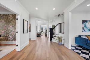 Foyer entrance with baseboards, light wood-style flooring, stairs, crown molding, and recessed lighting