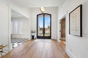 Entryway with french doors, ornamental molding, wood finished floors