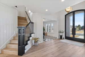 Foyer with stairs, french doors, wood finished floors, and recessed lighting