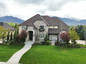 French provincial home with stone siding, a front lawn, and a mountain view