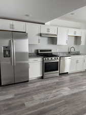 Kitchen featuring stainless steel appliances, under cabinet range hood, stone counters, and a sink