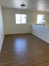 Unfurnished room with visible vents, baseboards, dark wood-style flooring, and a textured ceiling