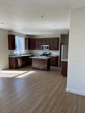 Kitchen featuring light countertops, light wood finished floors, appliances with stainless steel finishes, and a kitchen island