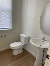 Half bath featuring baseboards, toilet, and wood finished floors