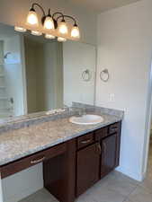 Bathroom featuring vanity,  shower combination, baseboards, and tile patterned flooring