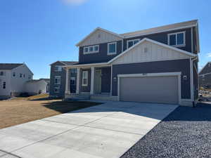 View of front of property featuring concrete driveway, a garage, covered porch, and board and batten siding