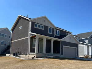 View of front of home featuring covered porch, an attached garage, central AC unit, and board and batten siding
