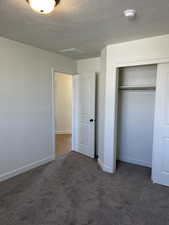 Unfurnished bedroom featuring a closet, baseboards, carpet, and a textured ceiling