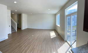Unfurnished room featuring light wood-style floors, baseboards, visible vents, and stairway