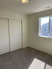 Unfurnished bedroom with a closet, visible vents, baseboards, and carpet