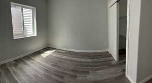 Unfurnished bedroom with a closet, dark wood-style floors, and baseboards