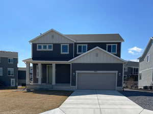 View of front of house featuring a garage, board and batten siding, concrete driveway, and a porch