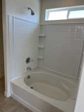 Full bath with tile patterned floors and shower / tub combination