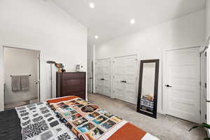 Bedroom featuring recessed lighting, light colored carpet, baseboards, and two closets