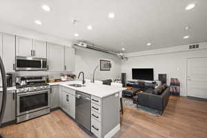 Kitchen featuring visible vents, gray cabinetry, a peninsula, stainless steel appliances, and a sink