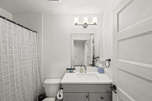 Bathroom with vanity, a shower with shower curtain, visible vents, a textured ceiling, and toilet