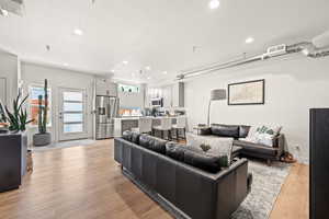 Living area with a wealth of natural light, visible vents, a textured ceiling, and light wood finished floors