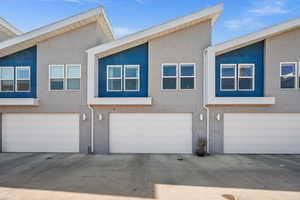 Multi unit property with stucco siding, driveway, and a garage