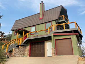 View of front facade featuring a balcony, a standing seam roof, an attached garage, concrete driveway, and metal roof