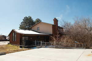 Rear view of property with covered porch and a chimney. Taken from NE side of property.