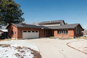 View of front of property featuring brick siding, concrete driveway, and an attached garage