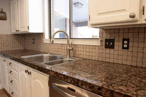 Kitchen with a sink, tile counters, decorative backsplash, white cabinetry, and stainless steel dishwasher