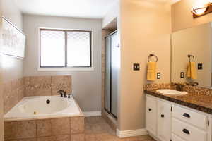 Full master bath with tile patterned floors, a tub with jets, a stall shower, and vanity