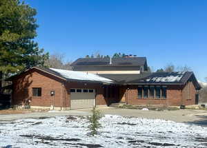 View of front of house featuring driveway, brick siding, and an attached garage