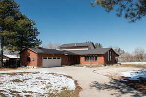 View of front of home with brick siding, concrete driveway, a garage, and fence