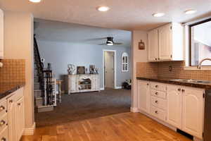 Kitchen featuring tasteful backsplash, light wood-style flooring, white cabinetry, and a sink