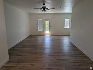 Empty room with baseboards, a textured ceiling, dark wood finished floors, and a ceiling fan