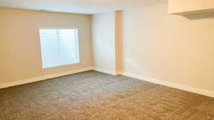 Spare room featuring carpet flooring and baseboards