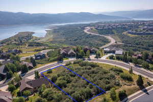 Aerial perspective of suburban area with property parcel outlined and a water and mountain view
