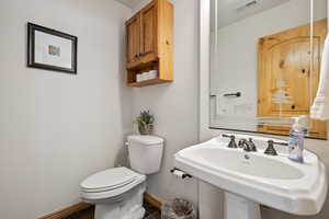 Half bath featuring toilet, a sink, visible vents, and baseboards