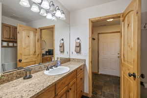 Bathroom featuring stone finish flooring, visible vents, vanity, and baseboards