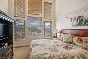 Bedroom with a high ceiling, baseboards, and carpet flooring