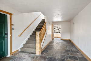 Stairway featuring baseboards, stone finish floor, and a textured ceiling